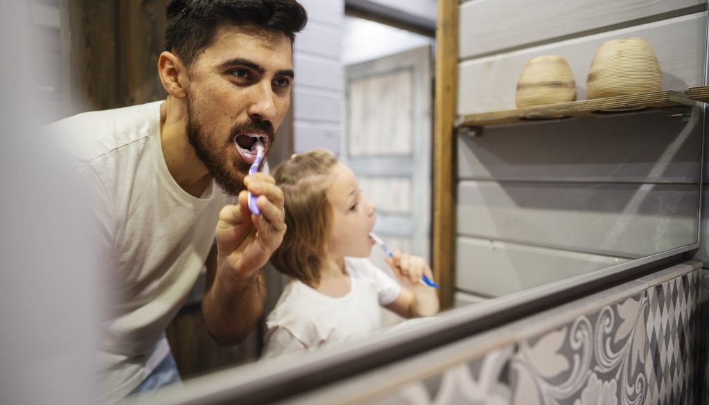 father and daughter brushing teeth