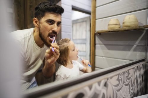 father and daughter brushing teeth